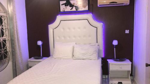 a bedroom with a white bed with purple lighting at Csompó Cozy One Bedroom Apartment Beach property in St Mary