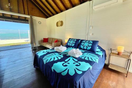 a bedroom with a bed with a blue comforter at Blackstone Paea Premium beachfront bungalow private access wifi - 3 pers in Paea
