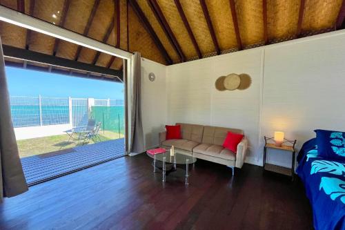 Habitación con sofá, cama y patio. en Blackstone Paea Premium beachfront bungalow private access wifi - 3 pers, en Paea