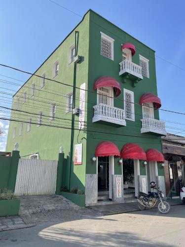 a green building with red balconies on a street at Hotel pousada porto real in Morretes