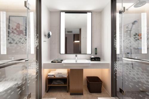 uma casa de banho com um lavatório e um espelho em Hampton by Hilton Beijing South Railway Station em Pequim
