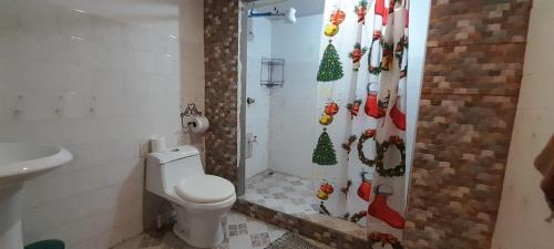 a bathroom with a toilet and a shower with a christmas shower curtain at Stay-ya, Diplo's Street in Puerto Limón