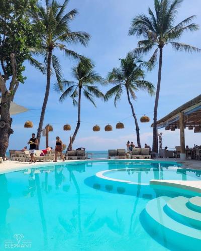 a swimming pool at the beach with palm trees at Elephant Beach Club & Resort Samui in Chaweng