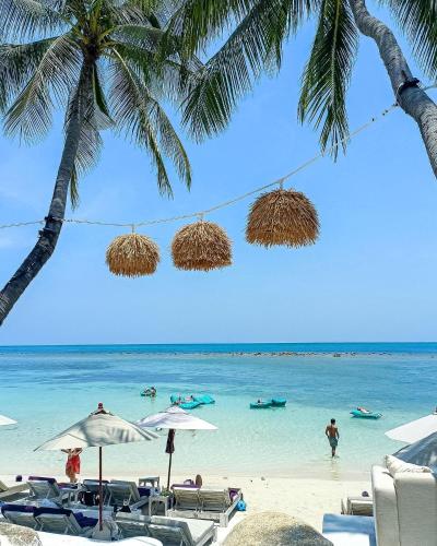 a beach with chairs and people in the water at Elephant Beach Club & Resort Samui in Chaweng