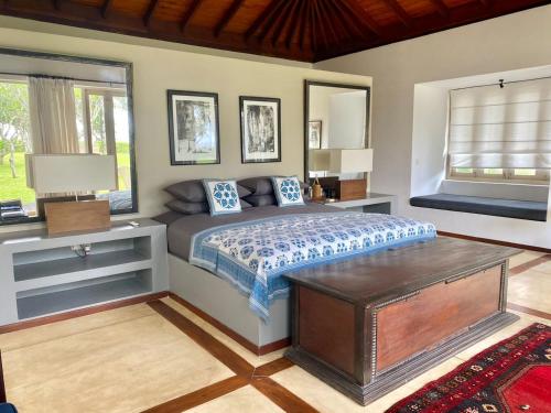 a bedroom with a bed and a table and windows at Elysium in Unawatuna