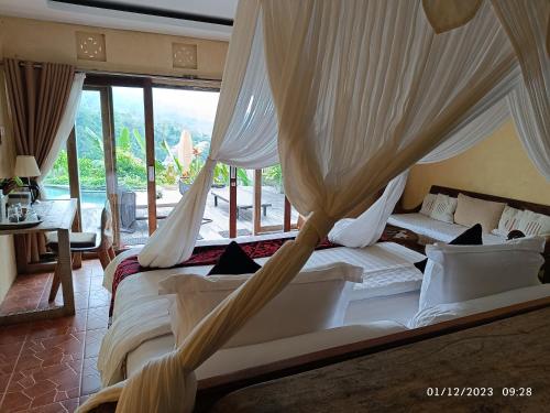 a bedroom with two beds with drapes at DWan Tea Mountain Side in Jatiluwih