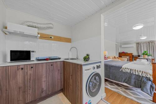 a kitchen with a washing machine next to a bed at Specious Studio W Gosford Centre in Gosford
