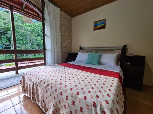 a bedroom with a bed and a large window at Hospedagem El Camino Del Viento in Teresópolis