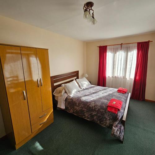 1 dormitorio con 1 cama y armario con cortinas rojas en Casa de familia en Ushuaia