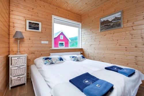 1 dormitorio con 1 cama grande en una cabaña de madera en Mjoeyri Travel Holiday Homes, en Eskifjörður
