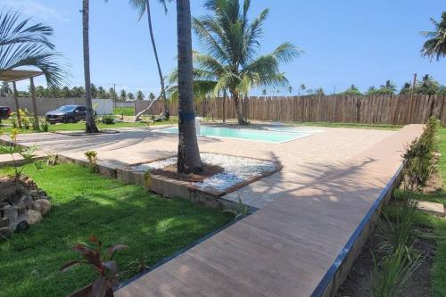 a backyard with a swimming pool and palm trees at Fantastiscos bangalôs em Aracaju in Aracaju