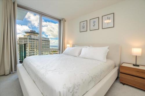 um quarto com uma cama branca e uma grande janela em Sky Ala Moana 2307 condo em Honolulu