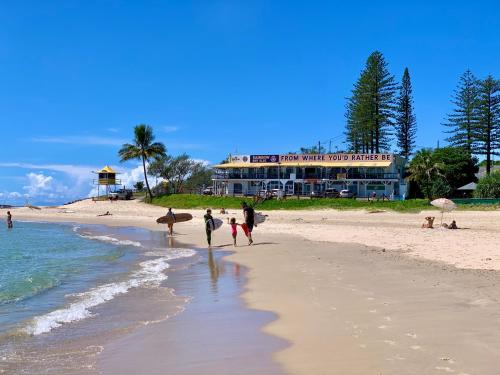 a group of people walking on the beach with surfboards at Surf Shack in Iconic Rainbow Bay - Coolangatta QLD (pet friendly) in Gold Coast