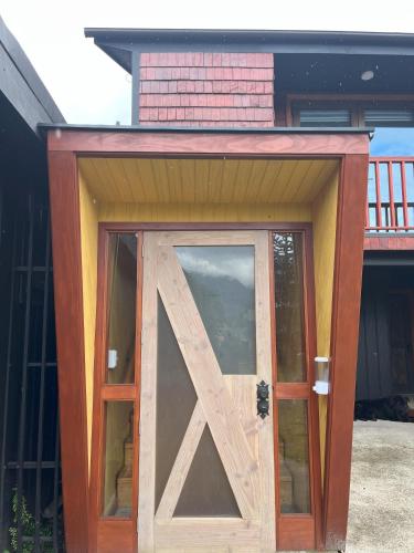 a wooden door with a window in front of a house at QUELEN AUSTRAL in Hornopiren