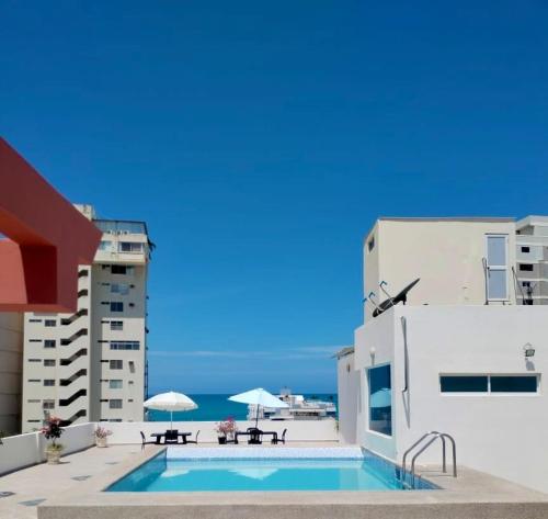 a swimming pool with tables and umbrellas on a building at DEPARTAMENTO, a una calle de la PLAYA Y MALECÓN in Salinas