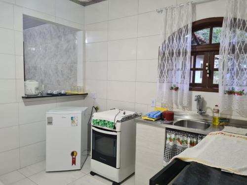 uma cozinha branca com um lavatório e um frigorífico em Hospedagem El Camino Del Viento em Teresópolis