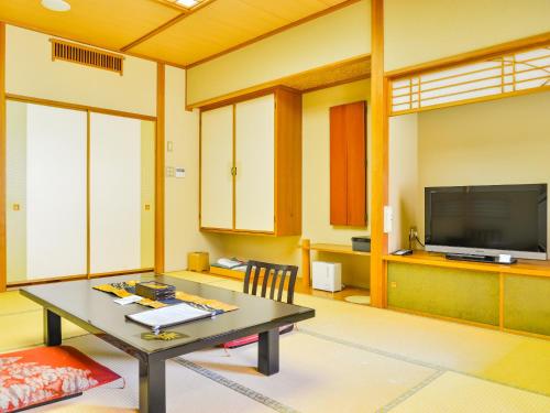 a living room with a table and a flat screen tv at Fudouonsen Sawaya in Shimojo mura