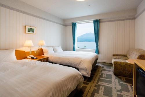 a hotel room with two beds and a window at Hotel Welview Kagoshima in Kagoshima