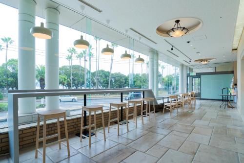 a row of tables and chairs in a room with windows at Hotel Welview Kagoshima in Kagoshima