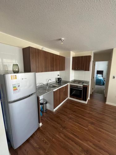 a kitchen with a white refrigerator and wooden cabinets at Cifmell Marina del Sol II in Talcahuano