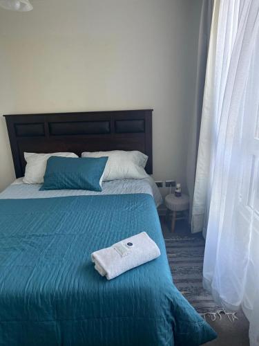 ein Bett mit einer blauen Decke und einem Handtuch darauf in der Unterkunft Cifmell Marina del Sol II in Talcahuano