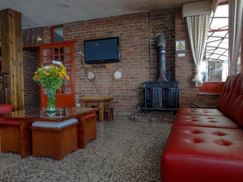 a living room with a red couch and a fireplace at Hotel Refugio Santa Ines in Aquitania