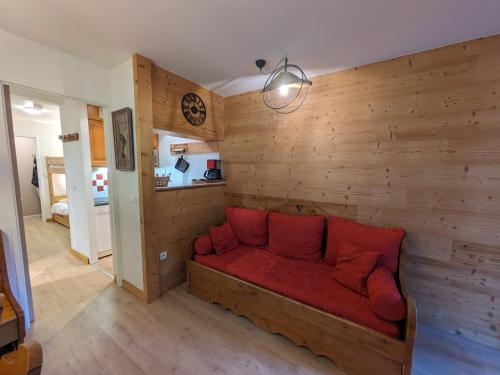 - un canapé rouge dans une chambre dotée de murs en bois dans l'établissement Charmant 2 pièces pour 4 personnes avec balcon et parking – Chamonix Sud, à 5 min du centre - FR-1-343-250, à Chamonix-Mont-Blanc