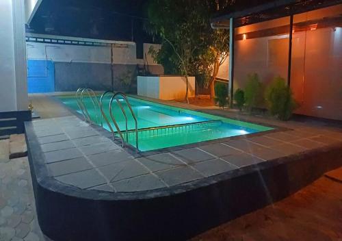 una piscina por la noche con luces verdes en Empire Pool Villa, en Meenangadi