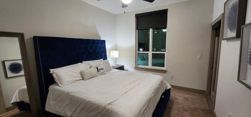 a bedroom with a bed with a blue headboard and a window at Stylish Downtown Retreat in Houston