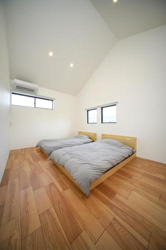 a bedroom with a bed and a wooden floor at BHOLIC（ビーホリック） in Shimonoseki