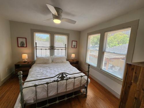 a bedroom with a bed with a fan and two windows at Cute & Quiet Garage Apt Home in Houston