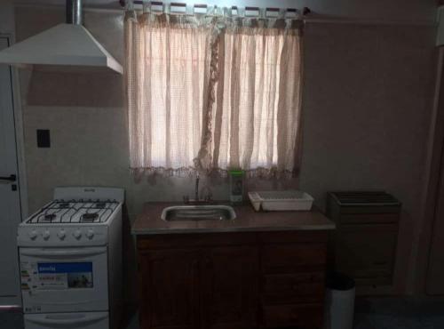 a kitchen with a sink and a stove and a window at Salta 869 in Mar de Ajó