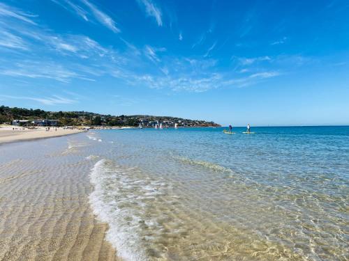a beach with the ocean and people in the water at The Sail House at Seacliff in Seacliff