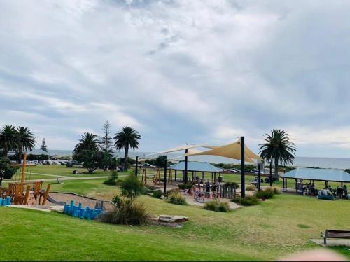 a park with tables and umbrellas on the grass at The Sail House at Seacliff in Seacliff