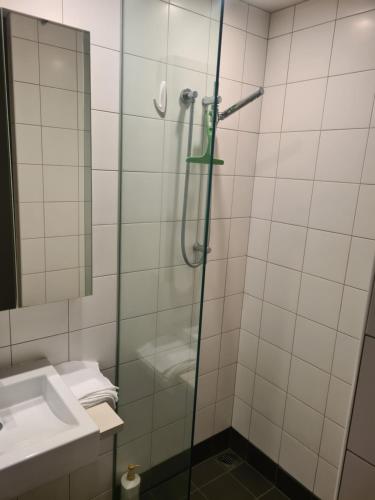 a shower with a glass door next to a sink at Boutique Hotel Complex Apartment with Hot Tub, Pool & Gym in Wellington