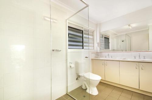 a white bathroom with a toilet and a sink at Ivory Palms Resort Noosa in Noosaville