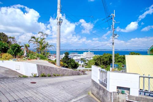 an empty street with the ocean in the background at Takashi House in Nanjo
