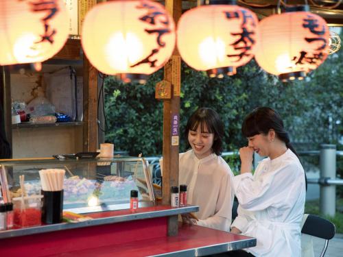 two women are standing at a counter in a restaurant at Prince Smart Inn Hakata in Fukuoka
