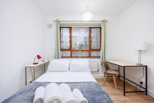 een slaapkamer met een bed, een bureau en een raam bij Kings Cross Suite in Londen