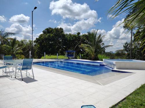 a swimming pool with a table and chairs next to it at FINCA HOTEL LA BONITA BY LA MACORINA in Quimbaya