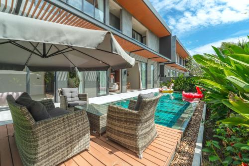 a patio with chairs and an umbrella next to a swimming pool at New 3BR Pool Villa Long One A5 with Chalong Bay view in Chalong