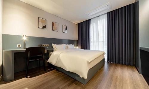 um quarto de hotel com uma cama e uma secretária e uma cama e uma cama em Pohang Hotel Noblion em Pohang