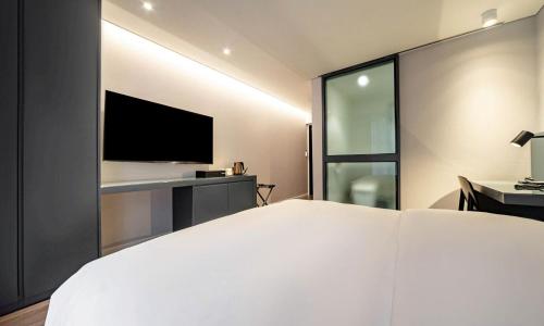 a bedroom with a large white bed and a tv at Pohang Hotel Noblion in Pohang