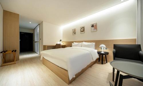 a bedroom with a large white bed and a table at Pohang Hotel Noblion in Pohang