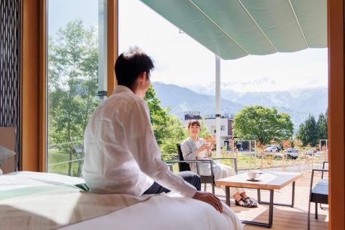 een man en een vrouw in een kamer met een raam bij グランコテージ白馬 in Hakuba