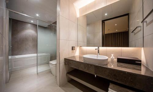 a bathroom with a sink and a toilet and a mirror at Pohang Hotel Noblion in Pohang