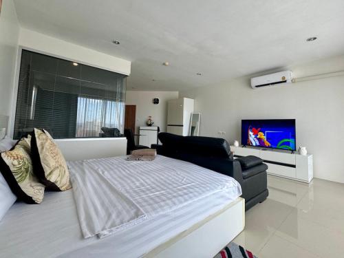 a bedroom with a large bed and a flat screen tv at Thawi Studio with Sea View in Chic Condo in Karon Beach