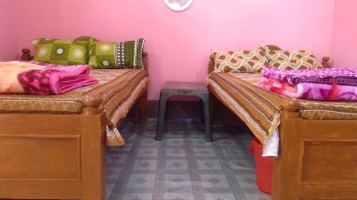 2 camas en una habitación con una pared de color rosa en Manas Ray Homestay, en Jyoti Gaon