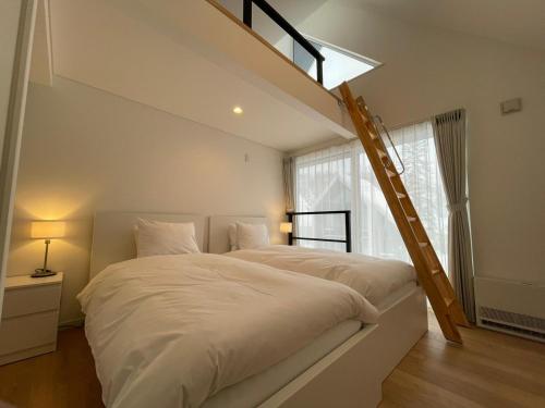 a bedroom with a large white bed with a ladder at Niseko STREAM Villas in Rankoshi