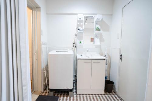 een witte badkamer met een wastafel en een spiegel bij Nagai park side stay in Osaka
